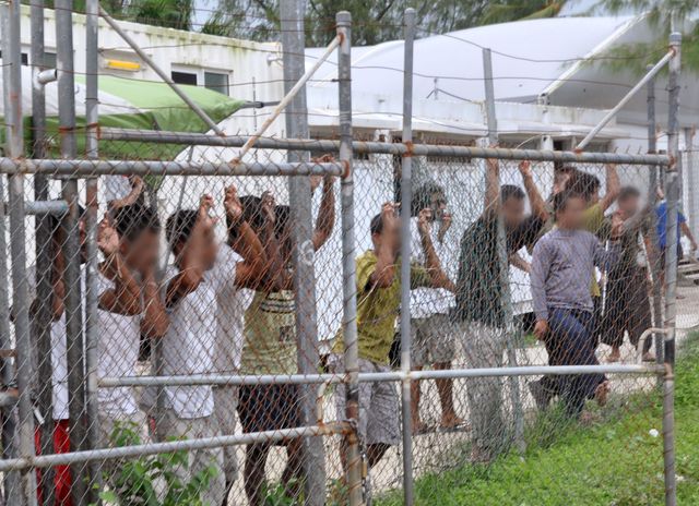asylum-seekers-look-at-the-media-from-behind-a-fence-at-the-manus-island-detention-centre-papua-new-guinea